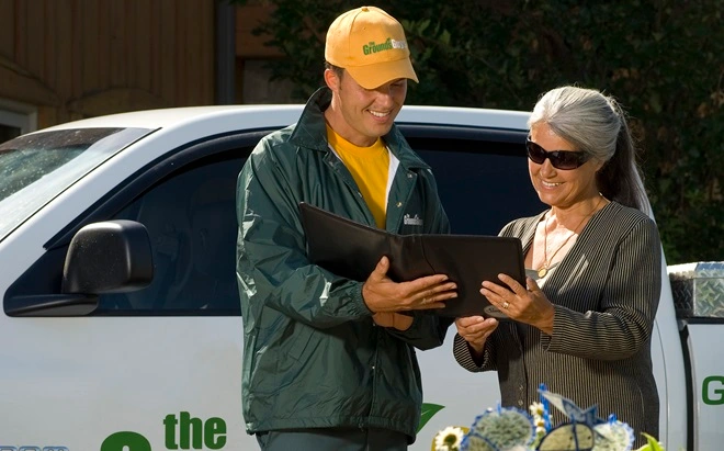 The Grounds Guys service professional looking at a tablet with a client.