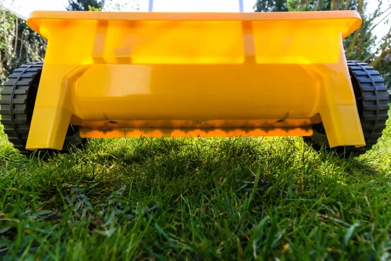 Close up image of a drop spreader tool on grass.