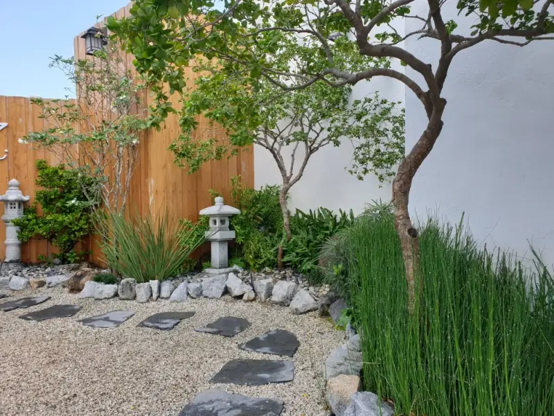 Zen garden in backyard with river rock landscaping.