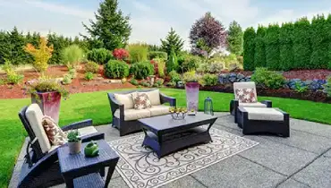 Backyard patio with furniture surrounded by greenery.