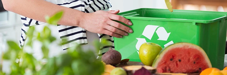 Person putting vegetables in a compost bin