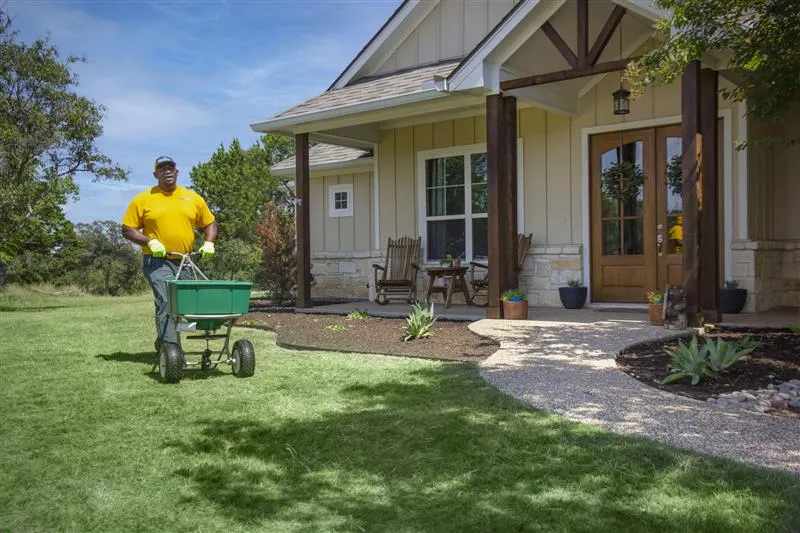 The Grounds Guys service professional fertilizing a homeowner's front lawn.