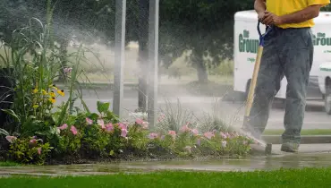 The Grounds Guys employee with a sprinkler