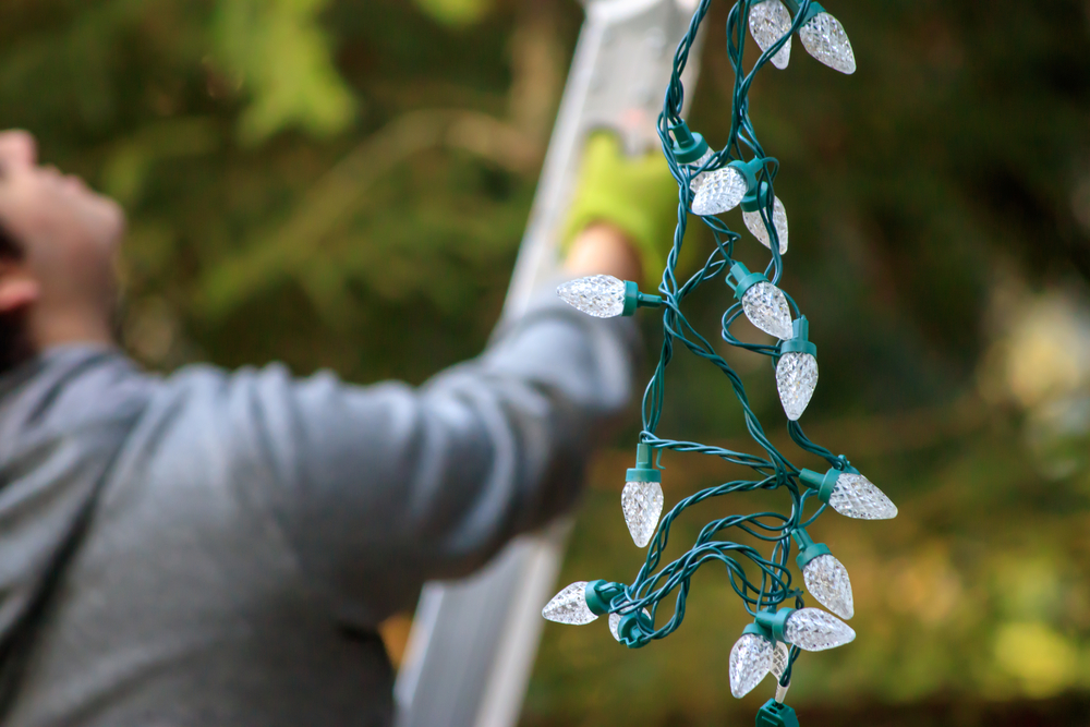 Man Hanging Holiday Lights with Ladder