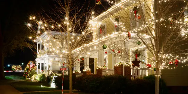 A home at night lit with white Christmas lights.